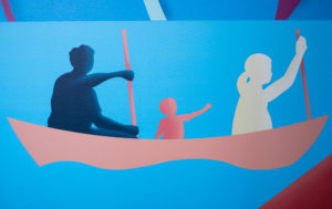 Close-up photograph of an interior mural, focusing on three silhouetted figures in a canoe set against a bright blue background.