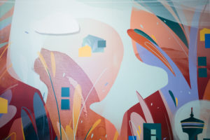 Close up photograph of an interior mural that features floral patterns with bright teal, orange, and red tones in a BMO office