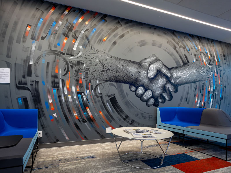 A digital vinyl mural in a bank lobby of two hands shaking by artist Rei Misir as part of the BMO National Mural Series by STEPS Public Art