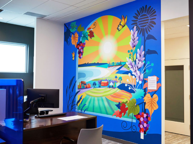 An interior digital vinyl mural by artist Steph Payne of a blue windowsill that overlooks a sunny scene of the countryside and water as part of the BMO National Mural Series by STEPS Public Art