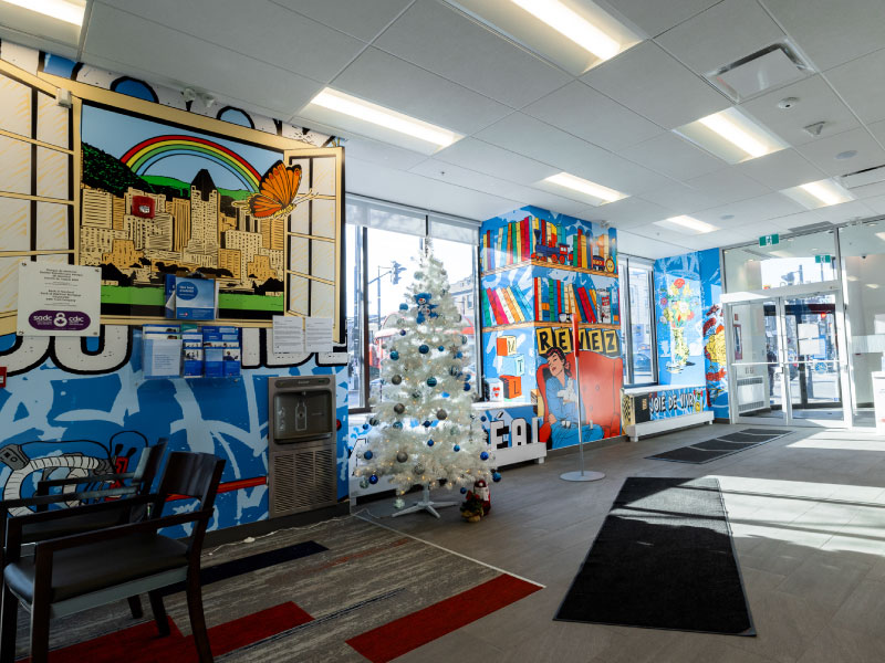 A series of interior digital vinyl murals by artist Whatisadam as part of the BMO National Mural Series. It depicts bookshelves and city views in a bright style.