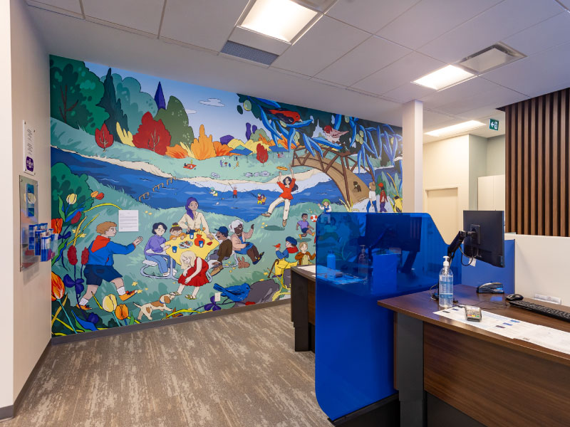 An interior vinyl mural by artist Yen Linh Thai depicting people having lunch by river and doing other activities in nature. This is part of the BMO National Mural Series by STEPS Public Art