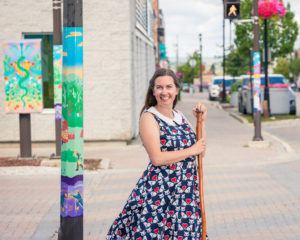 Artist Katherine Theresa Montigny posting beside her public artwork on a street pole in Timmins, Ontario