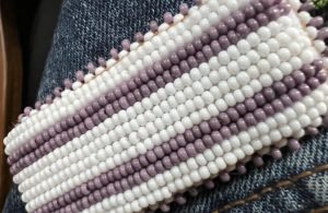 Beaded Wampum Belt with white & purple/grey beads in stripes, on a jean material by Lindsey Lickers.