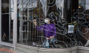 Artist Wenting Li drawing a window mural in Bloor West Village in Toronto