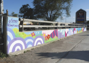 Jieun June Kim's colourful guardrail mural in Cooksville, Mississauga with STEPS Public Art and City of Mississauga. The mural has imagery of flowers, spiral circles, grassy hills, sparkly skies and staircases.