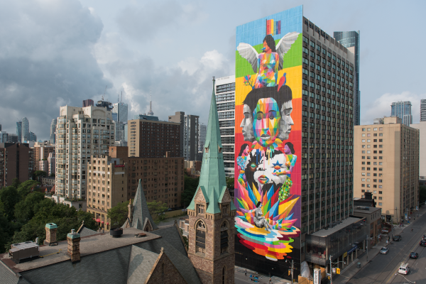 Equilibrium Mural by Okuda San Miguel in downtown Toronto featuring a colourful mural along a tall apartment building with colour blocking in rainbow colours and diverse faces and imagery