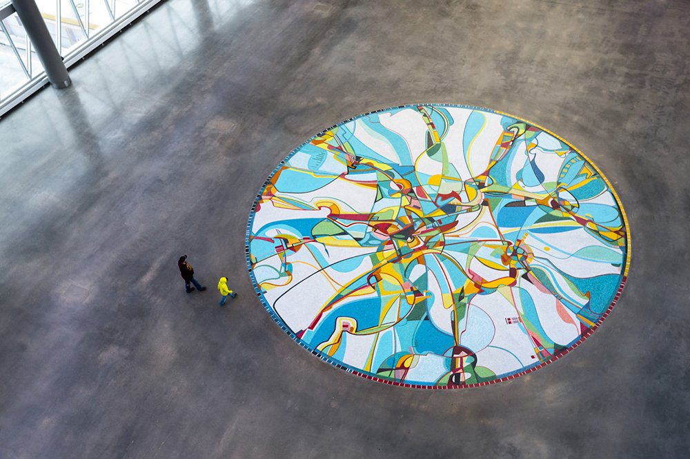 Aerial view of a circular mosaic glass installation on the floor of Edmonton's Rogers Place Arena