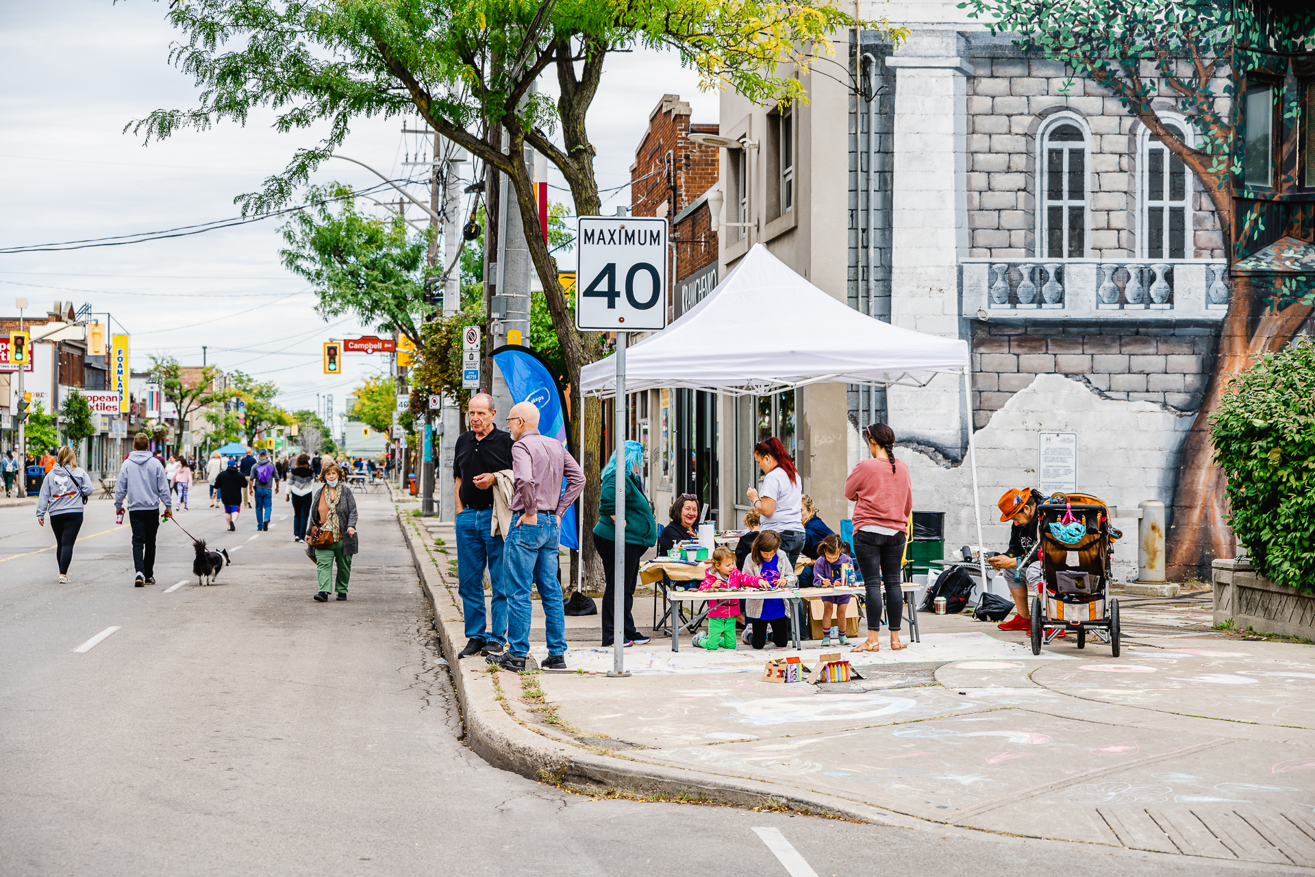 Residents enjoy the sidewalk festival in Hamilton, Ontario with artmaking and entertainment from the Ottawa Street BIA supported by I HeART Main Street