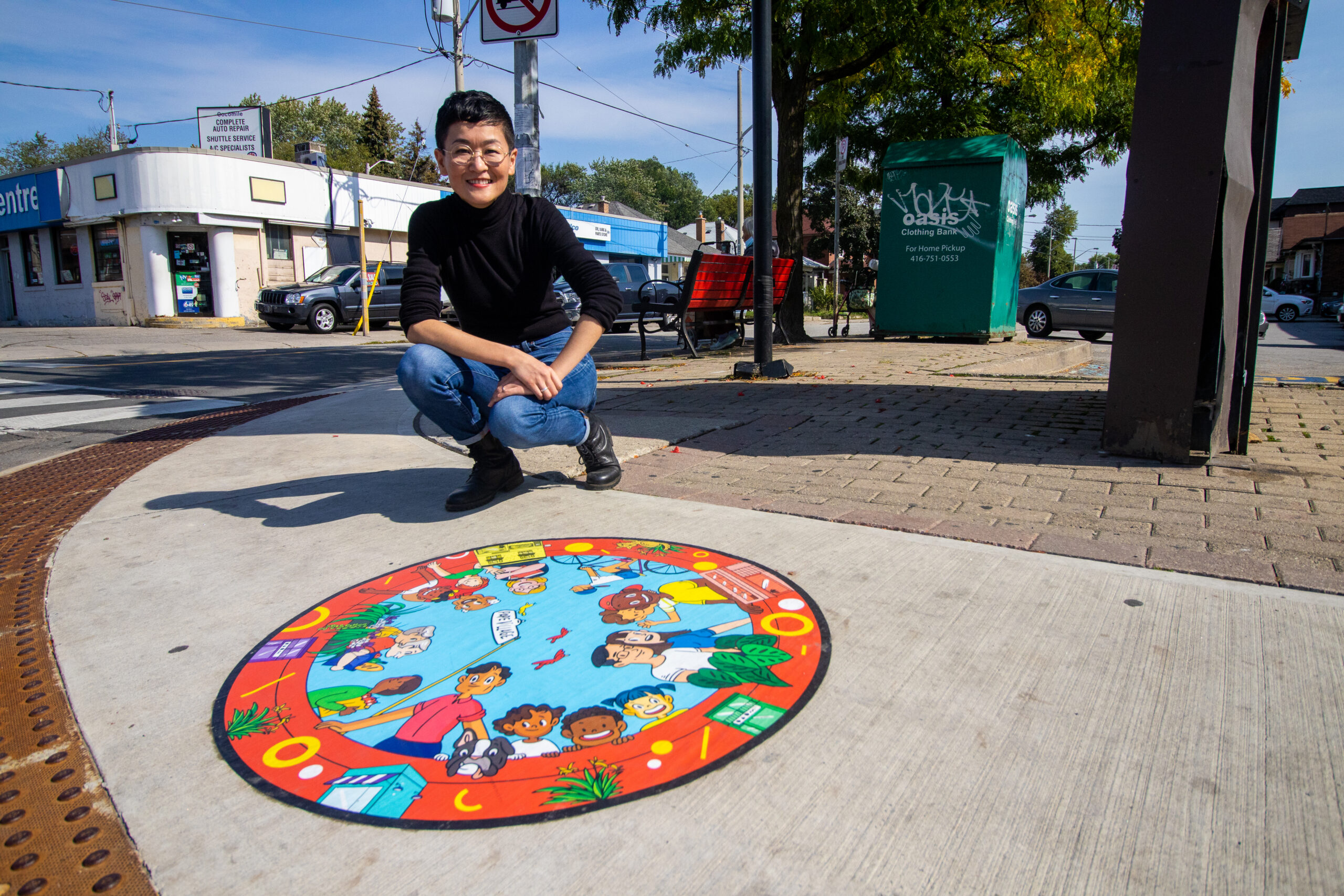 Suharu Ogawa poses with a sidewalk mural in Pape Village, Toronto