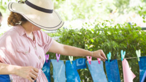 A person hanging cyanotyping prints on a clothesline outside