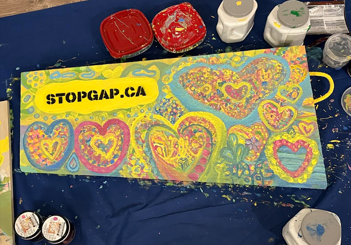 A yellow StopGap accessible ramp by artist Wendy Lu with pink and blue overlapping hearts painted. This is part of STEPS Public Art's Accessible Art and Placemaking Project