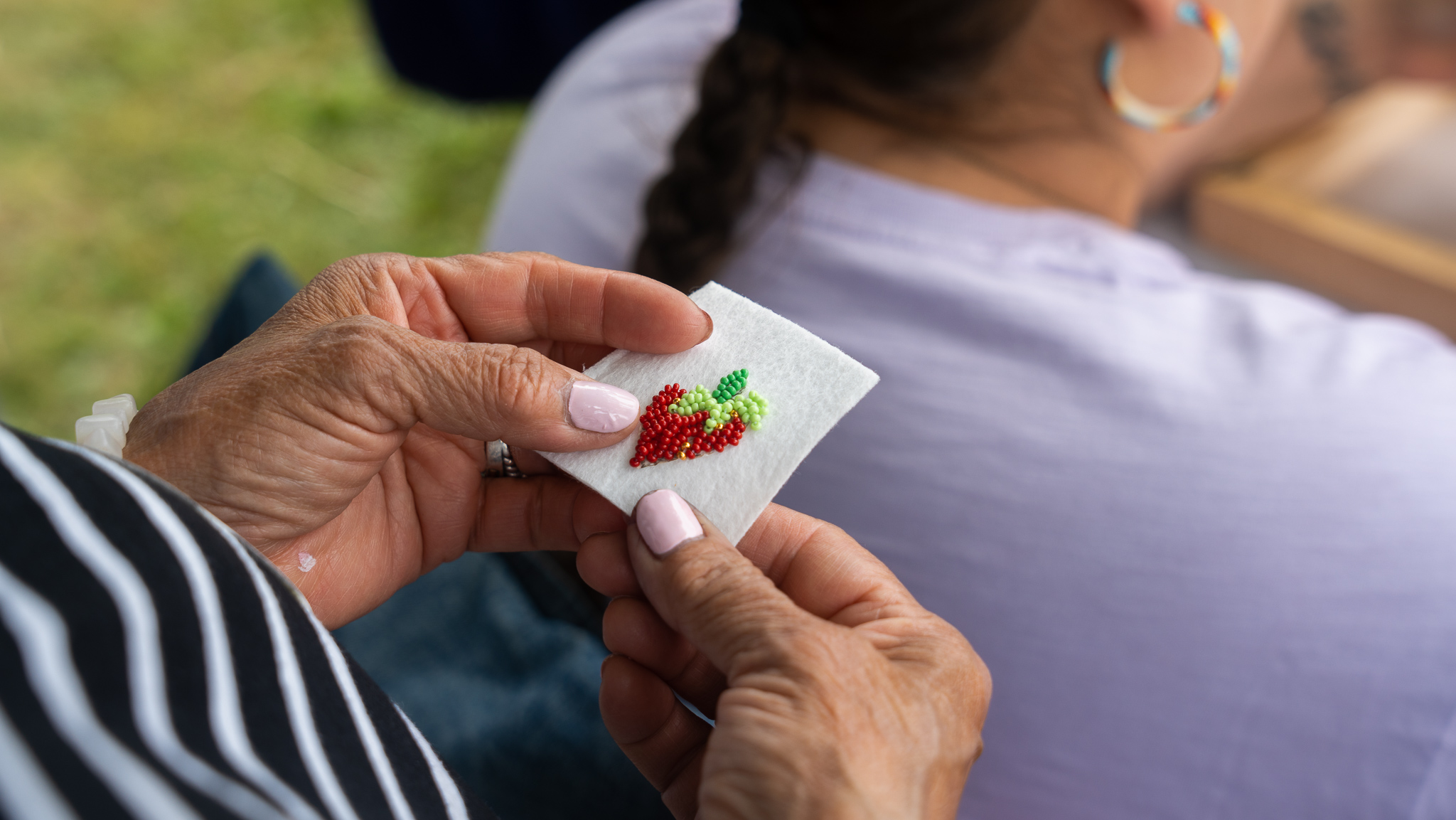 A participant holds a beaded strawberry at a free public beading workshop with STEPS led by Lindsey Lickers