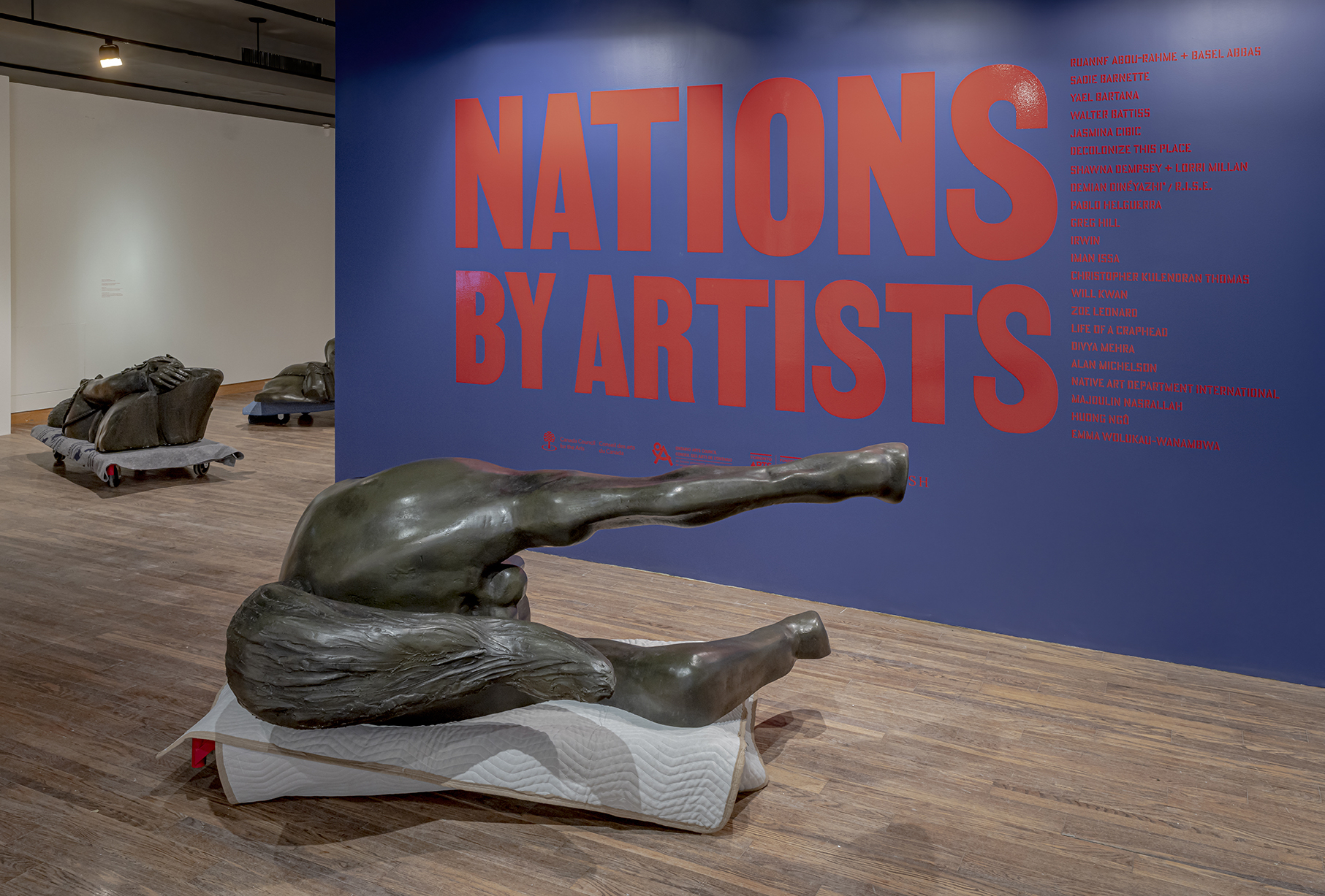 A monument replica is displaye din front of a sign for Nations by Artists exhibit at the Art Museum of University of Toronto