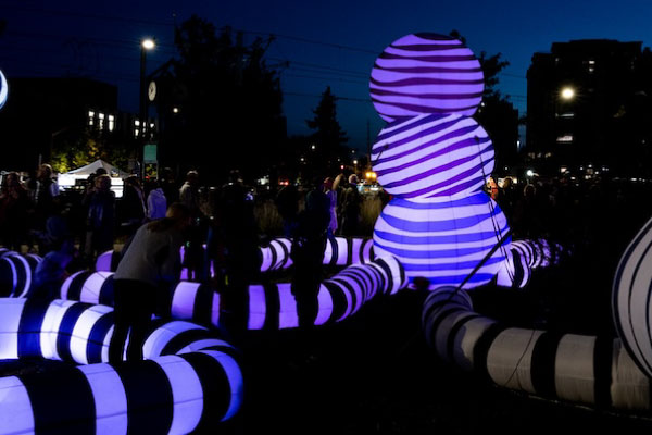 Large purple and black striped inflatable in an outdoor festival by LeuWebb and STEPS Public Art as part of the Lumen Festival