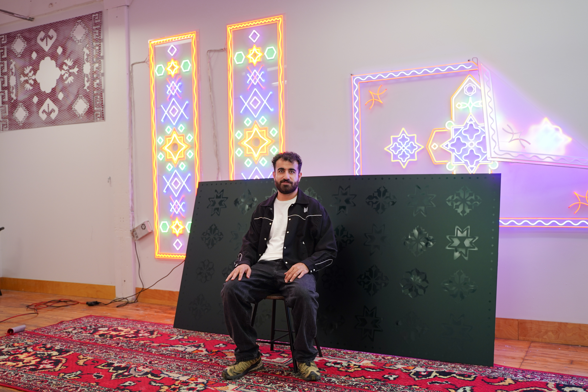 Roda Medhat seated in front of his rug sculptures hung up in his studio at 401 Richmond for an interview with STEPS Public Art