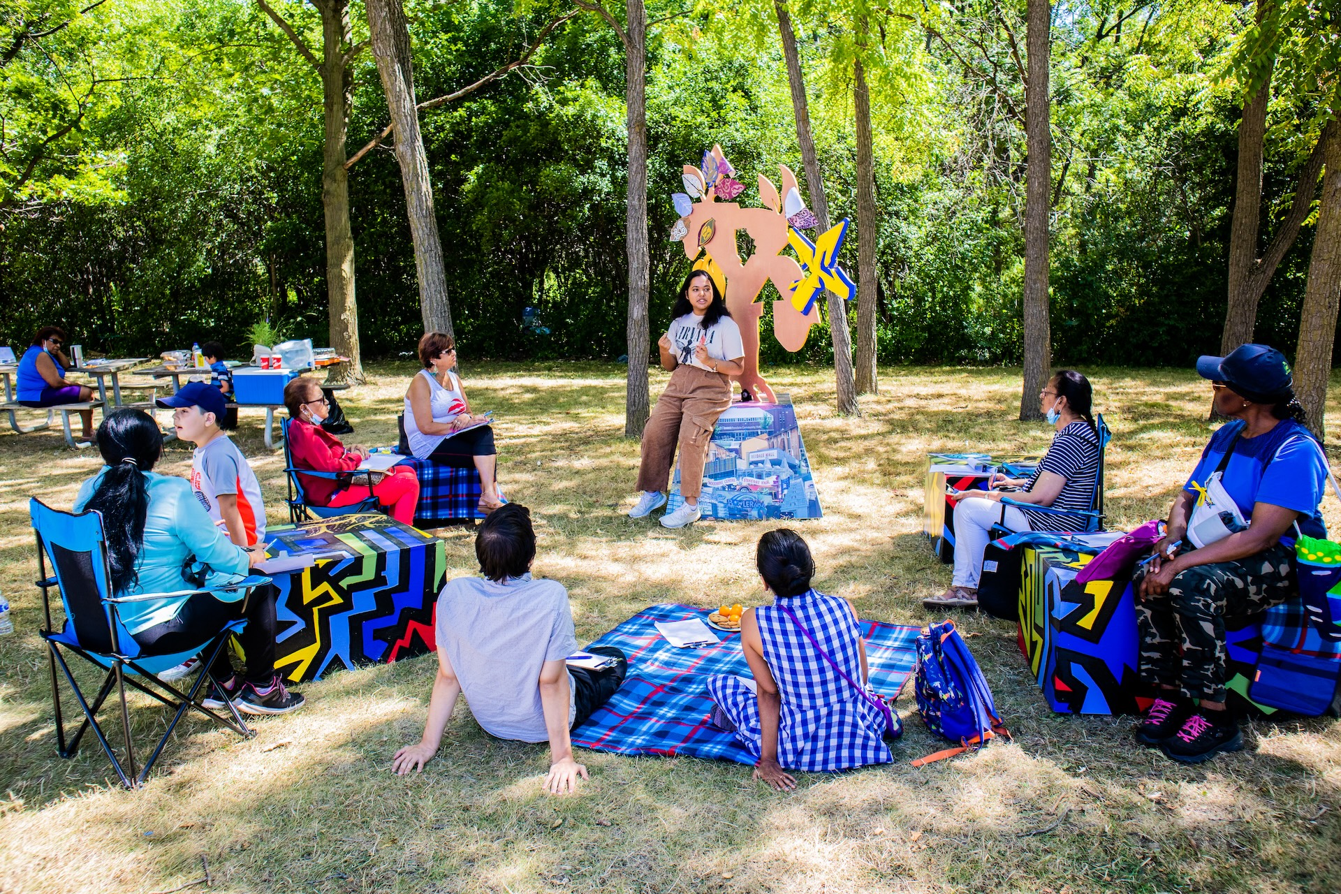 Community members sitting around a public art installation and listening to an artist speaking